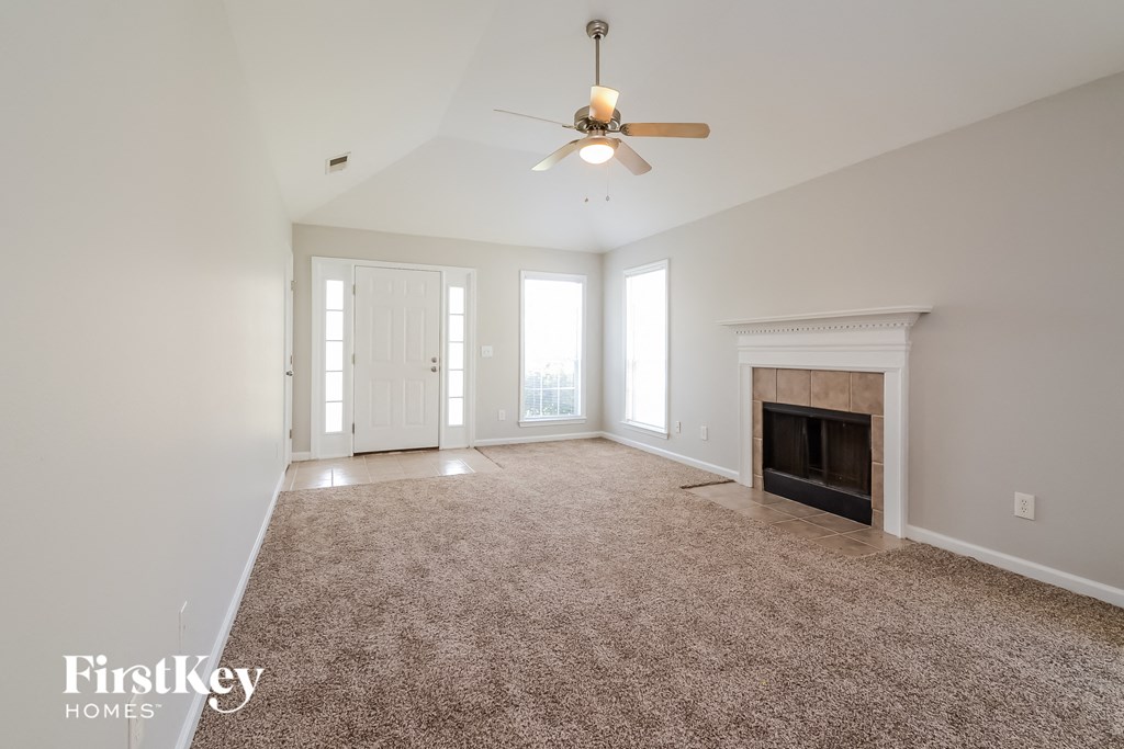 an empty living room with a ceiling fan and a fireplace