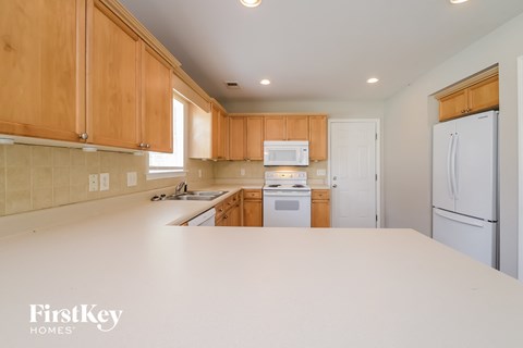 a kitchen with white counter top and wooden cabinets and white appliances
