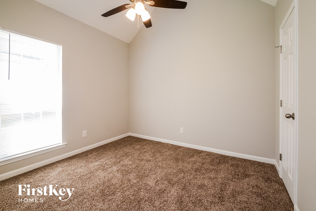 a carpeted room with a ceiling fan and a window