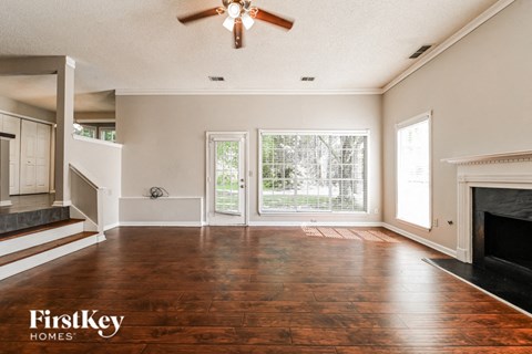 an empty living room with a fireplace and a ceiling fan