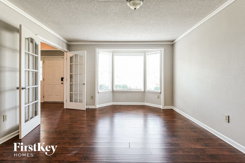 an empty living room with wood floors and a window