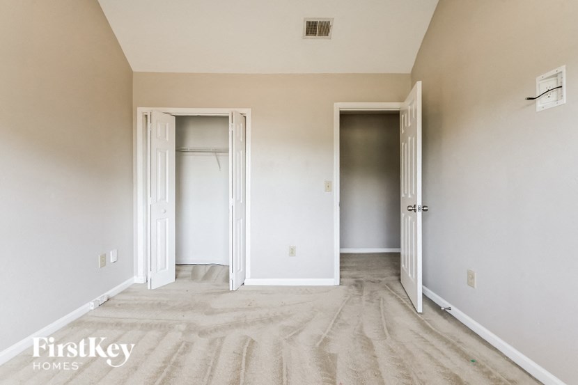 a bedroom with white walls and wood floors and two closets