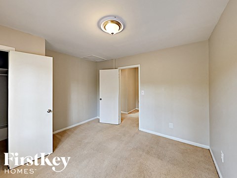 a bedroom with white walls and carpet and a door to a closet