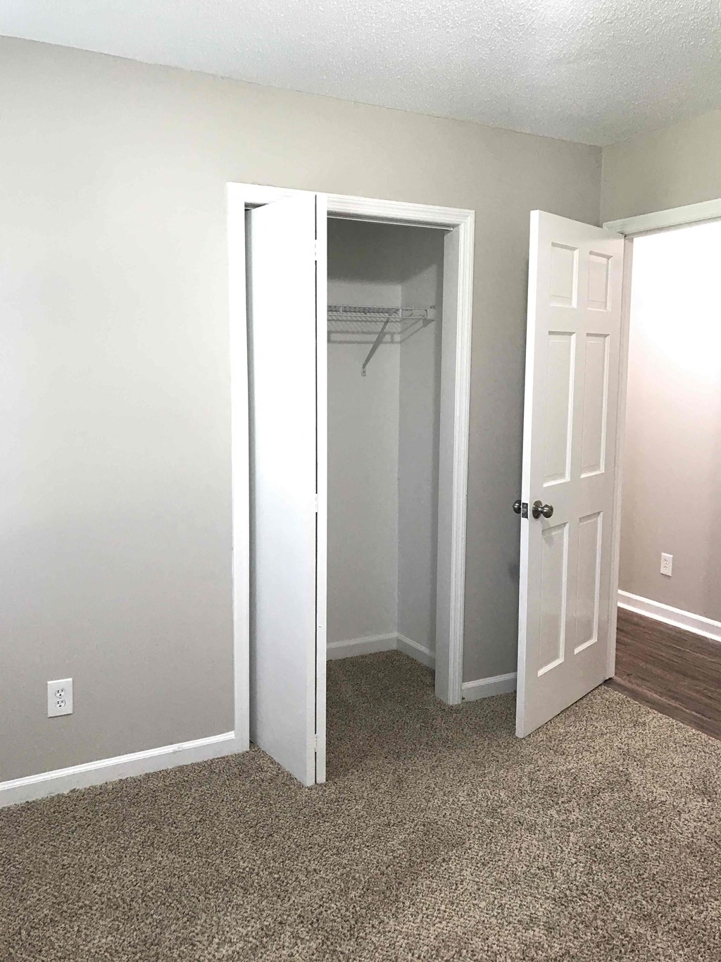 an empty bedroom with a closet and a door open