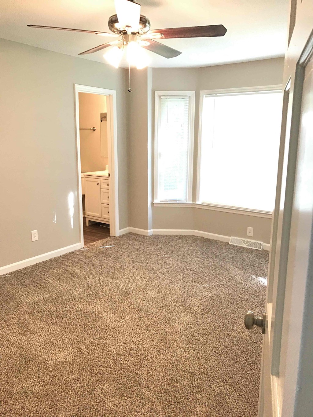 a room with a carpeted floor and a ceiling fan