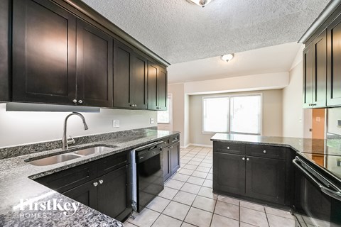 a kitchen with black cabinets and granite counter tops and a sink