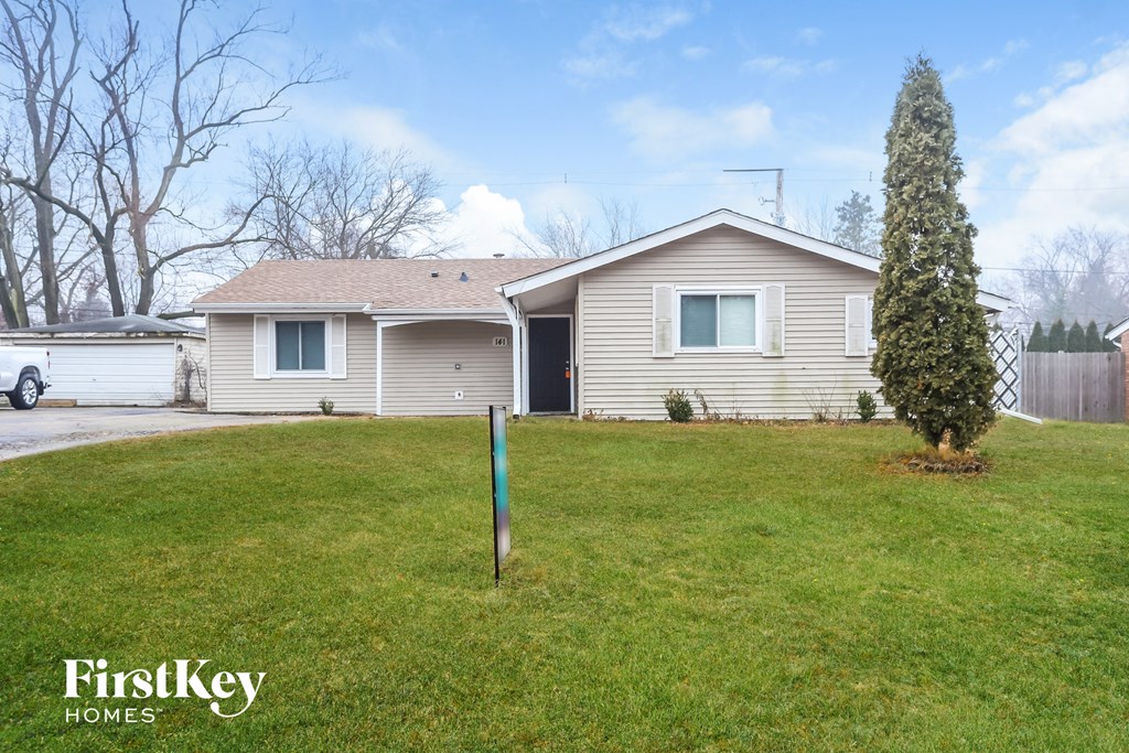 A house with a lawn and a tree in front of it.