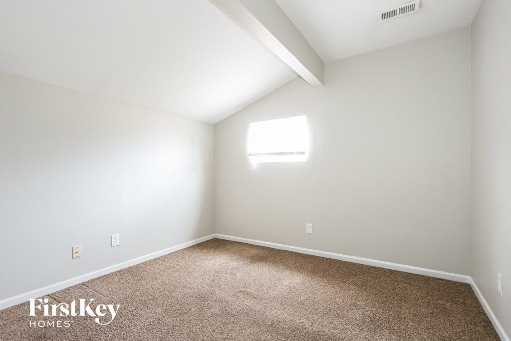 A room with a carpeted floor and a window letting in natural light.