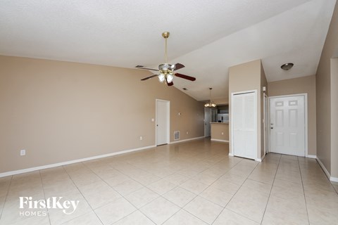 A spacious room with a ceiling fan and beige walls.