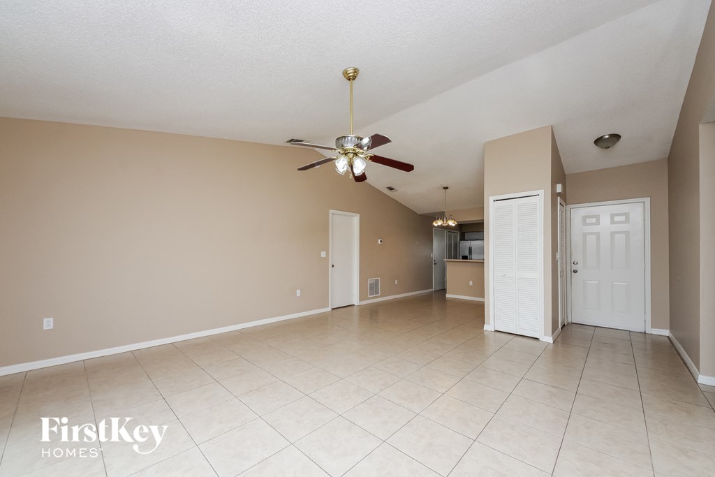A spacious room with a ceiling fan and beige walls.