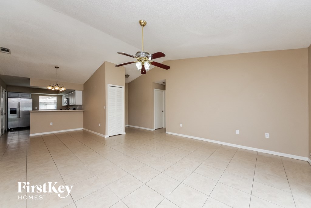 A spacious room with a ceiling fan and beige walls.