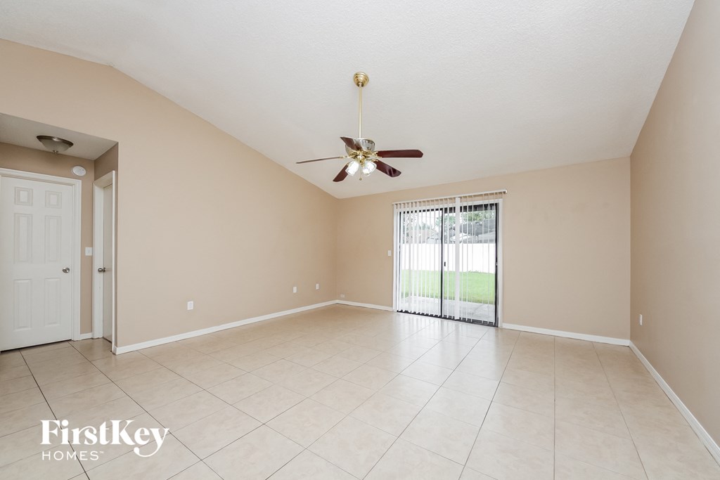 A spacious room with a ceiling fan and sliding glass doors leading to a balcony.