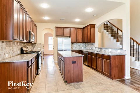 A kitchen with wooden cabinets and a tiled floor.