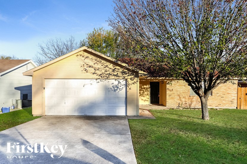 A house with a garage and a tree in front of it.