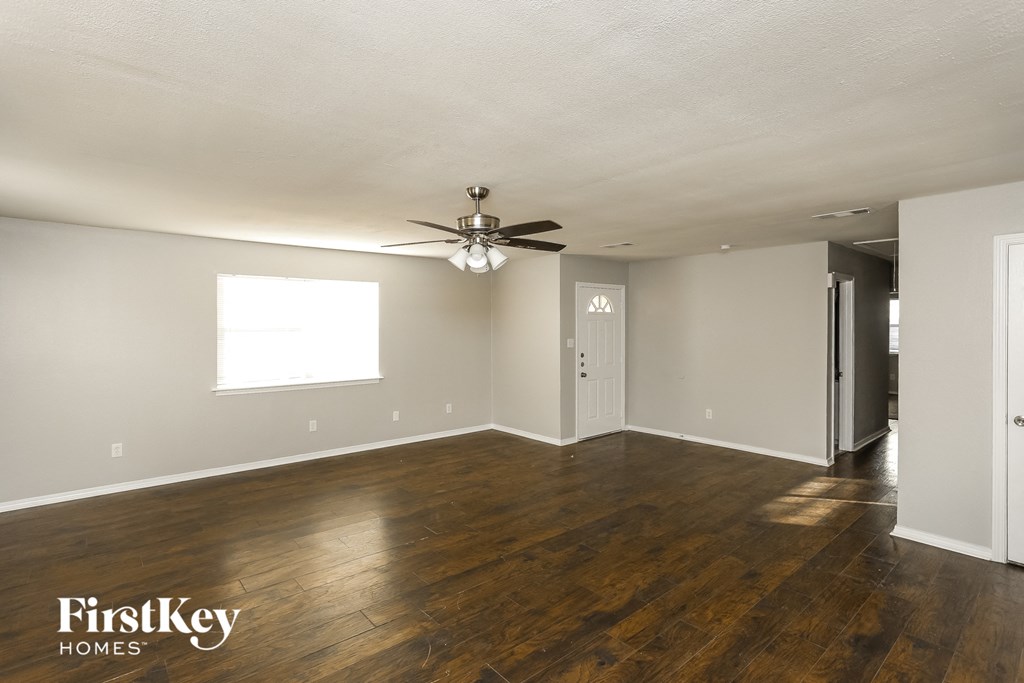 A spacious room with wooden floors and a ceiling fan.