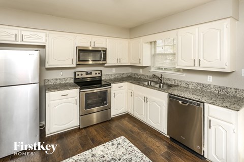 A kitchen with white cabinets and granite countertops.