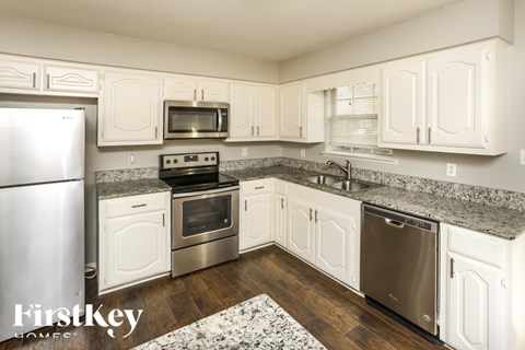 A kitchen with white cabinets and a granite countertop.