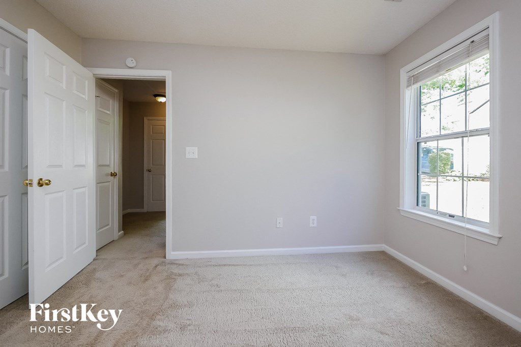 a bedroom with a carpeted floor and a white door and window