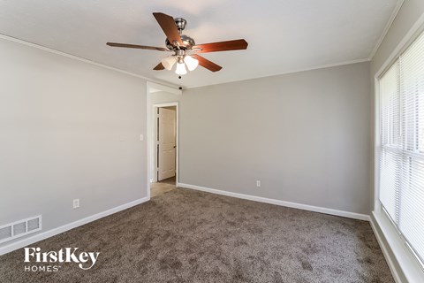 a living room with a ceiling fan and a carpet