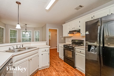 A kitchen with wooden floors and white cabinets.