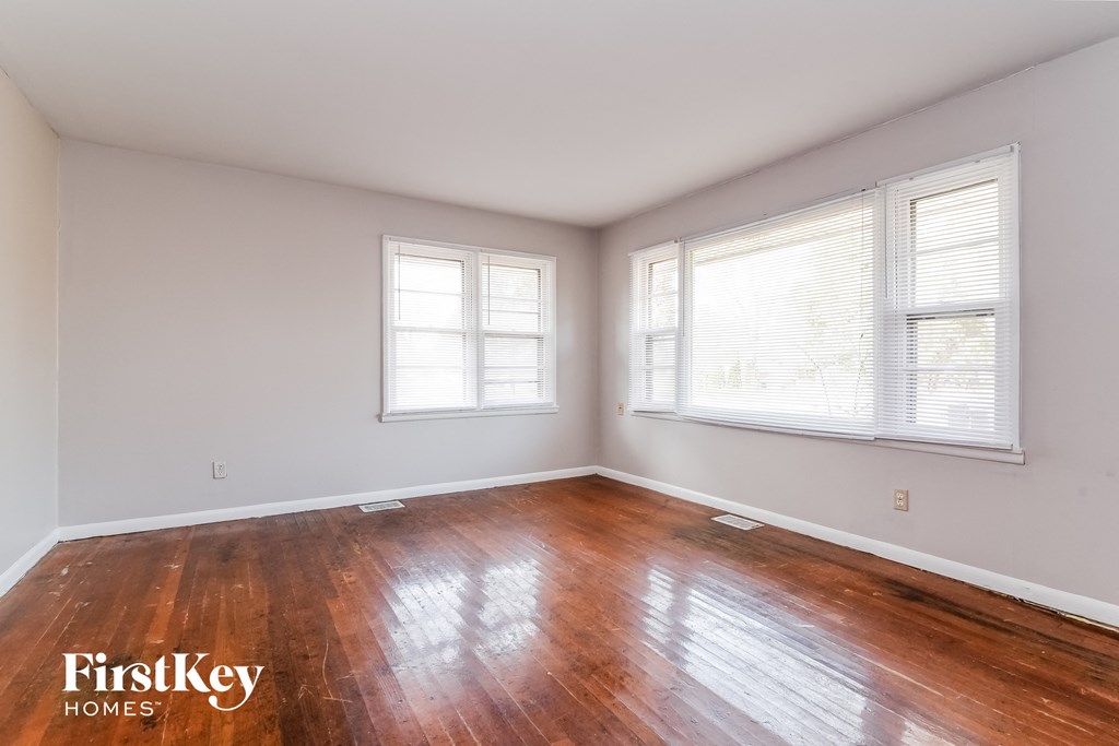 A room with wooden floors and two windows.