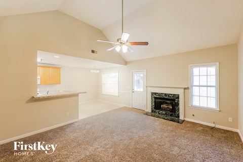 A spacious living room with a fireplace and a ceiling fan.