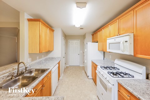 A kitchen with wooden cabinets and a white stove top oven.