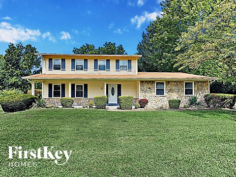 a yellow house with a green lawn and trees
