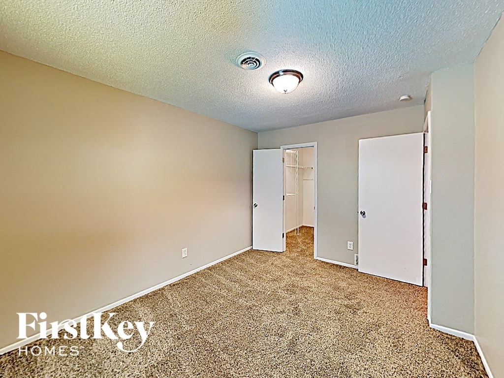 a bedroom with a carpeted floor and a door to a closet