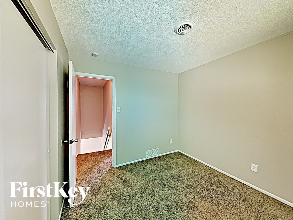 an empty bedroom with a door to a pink closet