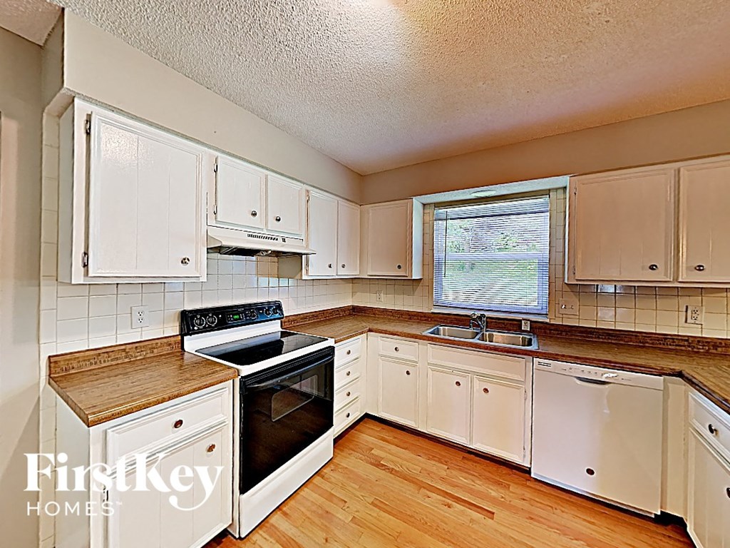 a kitchen with white cabinets and a stove and a sink