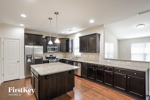 A kitchen with dark wood cabinets and a granite countertop.