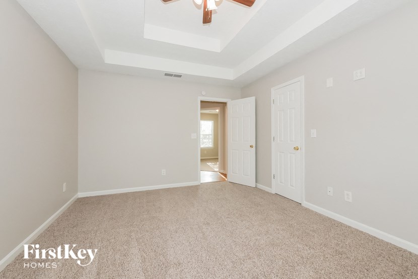 a spacious living room with carpet and a ceiling fan