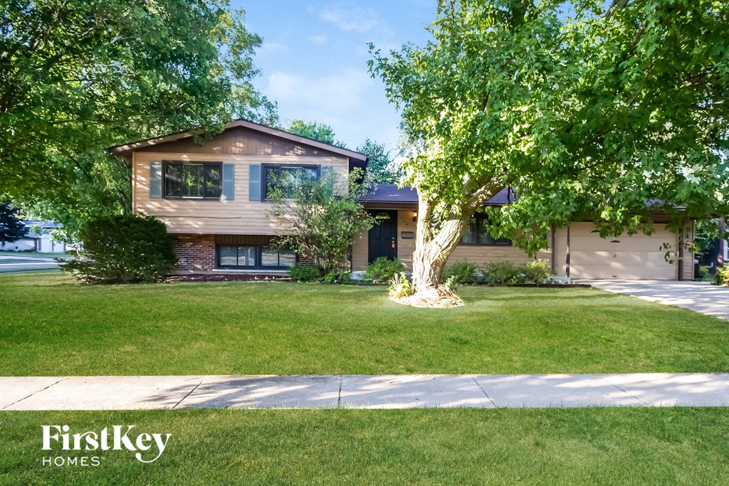 A house with a brown roof and a tree in front of it.