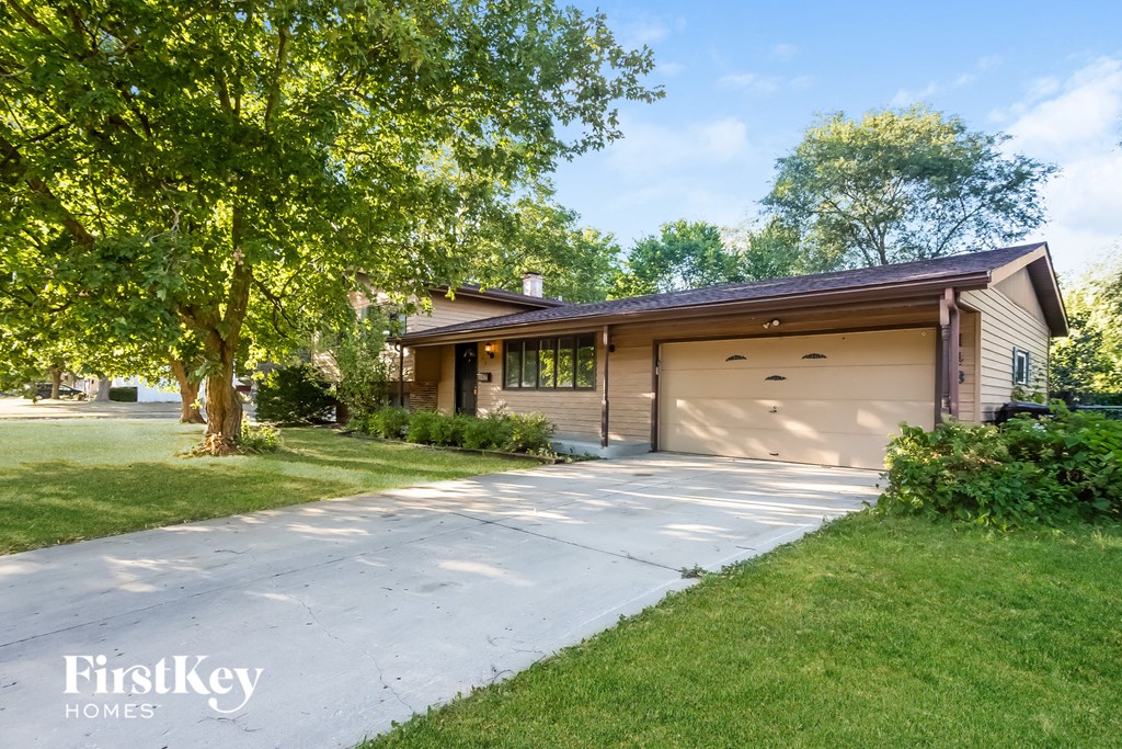 A house with a garage is surrounded by greenery.