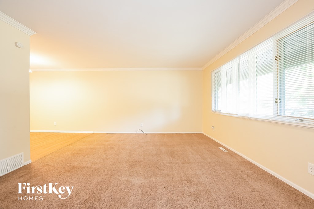 A room with a carpeted floor and a window with blinds.