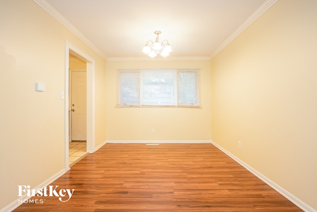A room with wooden floors and a window with blinds.