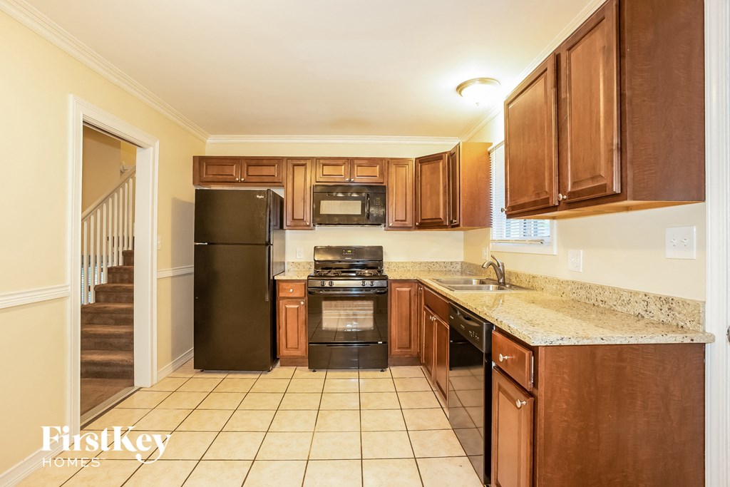 A kitchen with brown cabinets and a black fridge.