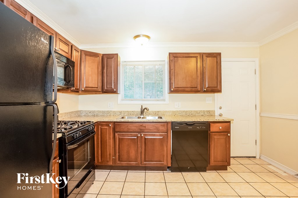 A kitchen with wooden cabinets and a black refrigerator.