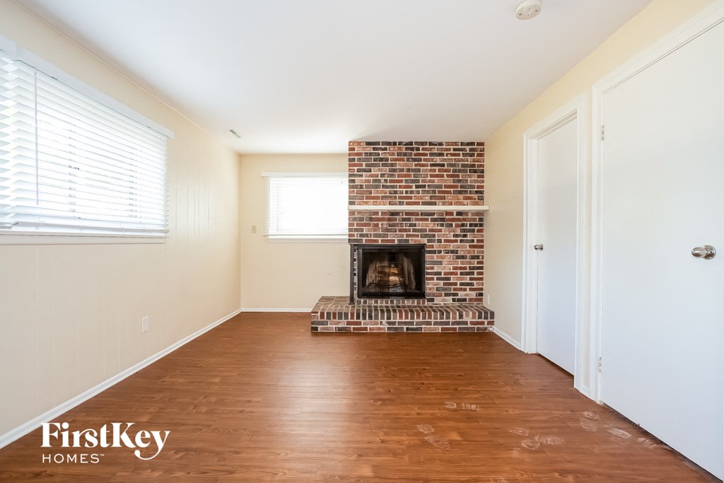 A room with a brick fireplace and wooden floors.
