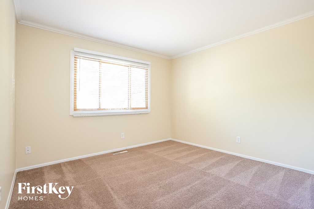 A room with a carpeted floor and a window with blinds.