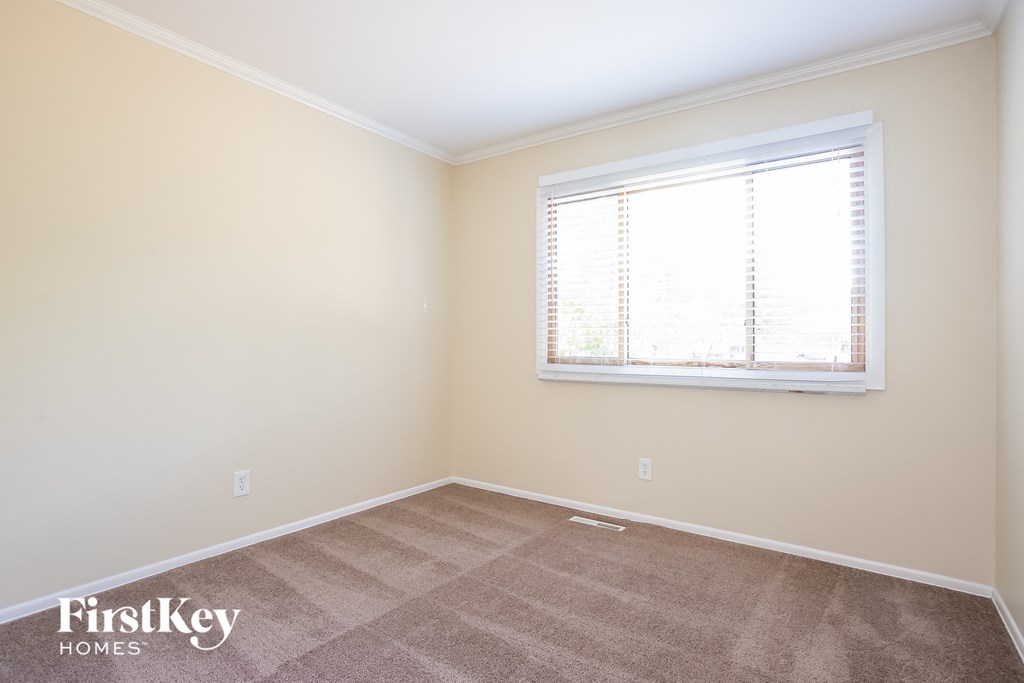 A room with a carpeted floor and a window with blinds.