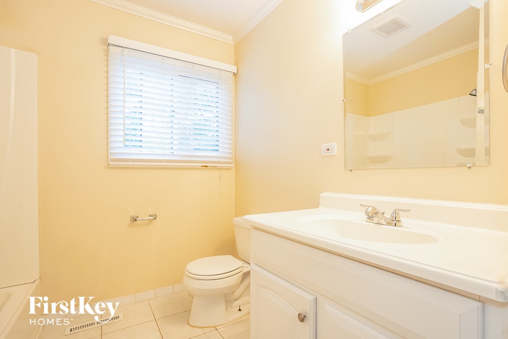 A bathroom with a toilet, sink, and mirror.