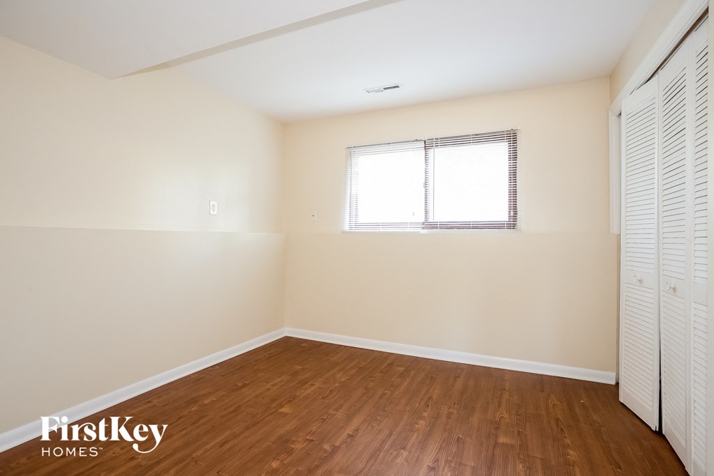 A room with wooden floors and a window with blinds.