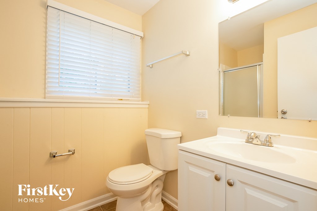 A bathroom with a toilet, sink, and mirror.
