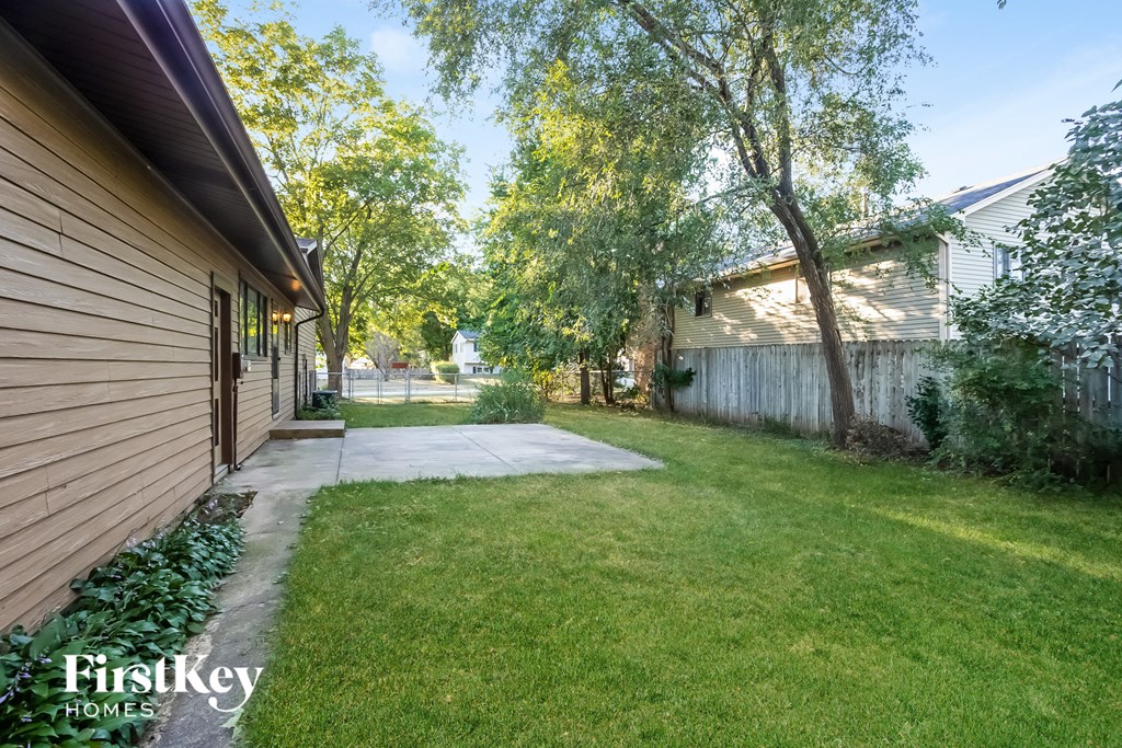 A sunny day at a residential area with a house and a tree in the foreground.