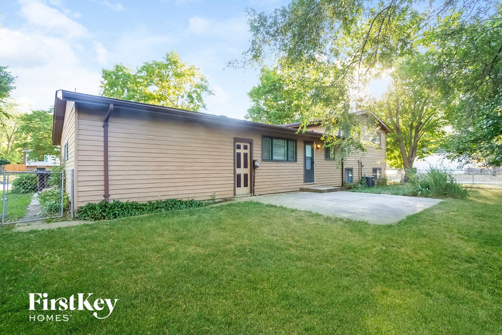 A house with a brown siding and a green lawn in front.