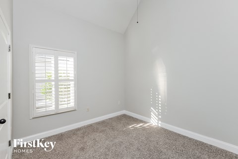 a bedroom with white walls and carpet and a window