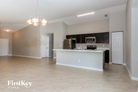 A spacious kitchen with a white island and a black refrigerator.