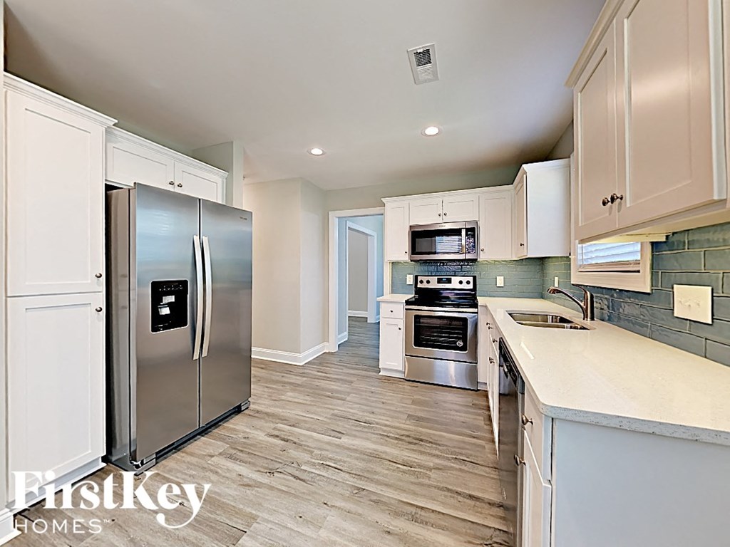A kitchen with a refrigerator, oven, and microwave.